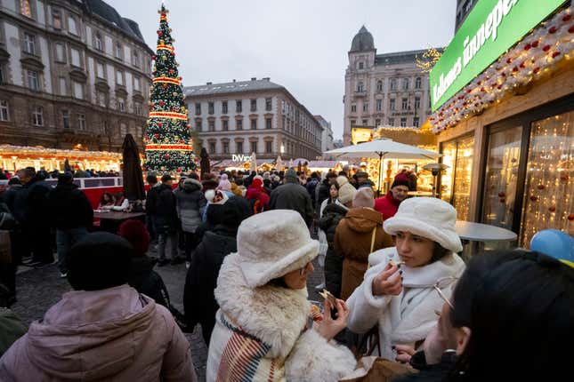 Visitors eat Chimney Cake, a traditional Hungarian festive food at one of Europe&#39;s most famous outdoor Christmas markets, the Advent Bazilika market in downtown Budapest, Hungary, Saturday, Dec 9. 2023. (AP Photo/Denes Erdos)