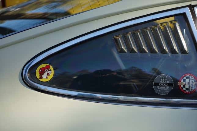 A louvered side window on a classic Porsche 911 with a Buccees sticker