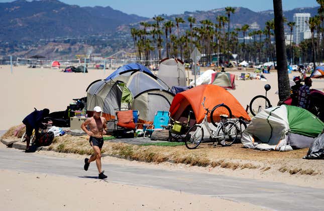 FILE - In this June 8, 2021, file photo, a jogger runs past a homeless encampment in the Venice Beach section of Los Angeles. By the end of the century, the U.S. population will be declining without substantial immigration, senior citizens will outnumber children and the share of white residents who aren&#39;t Hispanic will be less than half of the population, according to population projections released Thursday, Nov. 9, 2023 by the U.S. Census Bureau. (AP Photo/Marcio Jose Sanchez, File)