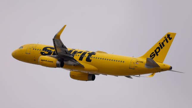 Un avion jaune de Spirit Airlines vole dans un ciel gris