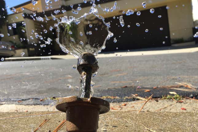 A sprinkler shoots water next to a residential home in California.