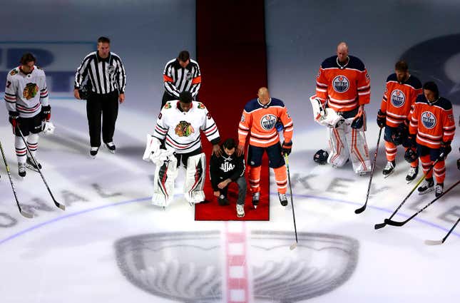  Malcolm Subban #30 of the Chicago Blackhawks and Darnell Nurse #25 of the Edmonton Oilers place their hands on Mathew Dumba of the Minnesota Wild during the national anthem of the United States before the Game One of the Western Conference Qualification Round prior to the 2020 NHL Stanley Cup Playoffs at Rogers Place on August 01, 2020 in Edmonton, Alberta.