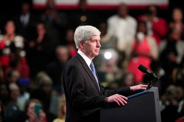 Michigan Governor Rick Snyder stands and listens to the boos of the crowd when he takes to the stage to speak before U.S. President Barack Obama speaks at Northwest High School about the Flint water contamination crises 