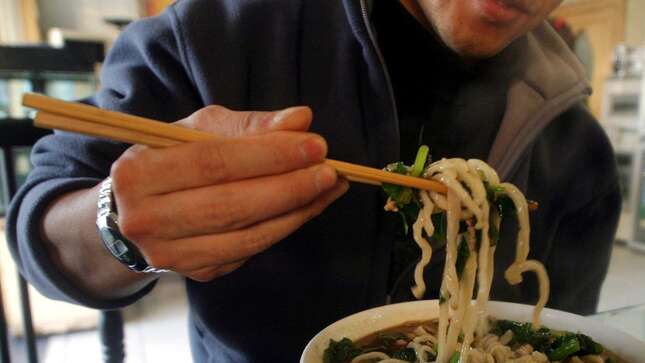 In this Nov. 20, 2003 file picture, a man uses chopsticks to eat noodles at a restaurant in Beijing, China.