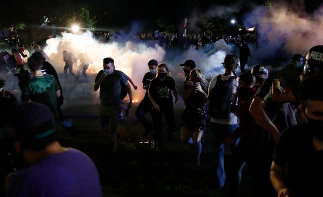 Protestors run for cover as police shoot tear gas in an effort to disperse the crowd outside the County Courthouse during demonstrations against the shooting of Jacob Blake in Kenosha, Wisconsin on August 25, 2020.