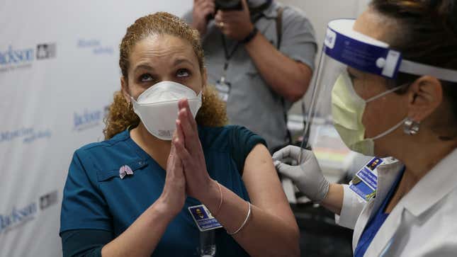 Elizabeth Plasencia, RRT Medical Hospital Center at the Jackson Health Systems, clasps her hands together after receiving a Pfizer/BioNtech covid-19 vaccine from Susana Flores Villamil, RN from Jackson Health Systems, at the Jackson Memorial Hospital on December 15, 2020 in Miami, Florida. 