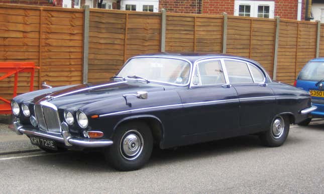 A dark colored Jaguar MK X parked on a road