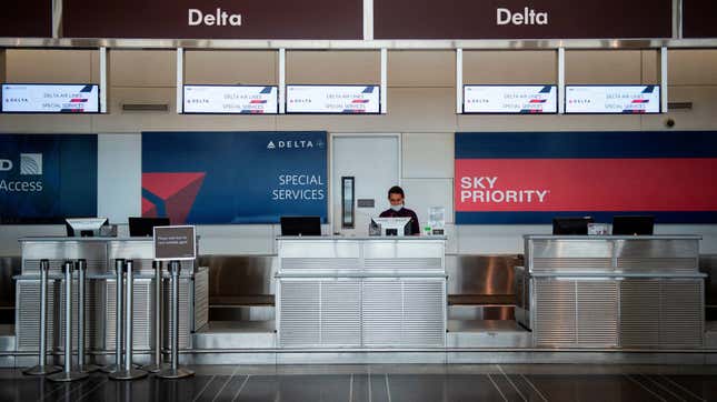 A Delta airlines employee waits for passengers at an empty check-in counter in Ronald Reagan Washington National Airport in Arlington, Virginia, on May 12, 2020.