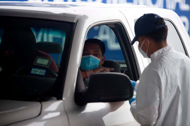 A healthcare worker talks to a person in line in their vehicle at United Memorial Medical Center Covid-19 testing site in Houston, Texas, June 25, 2020.