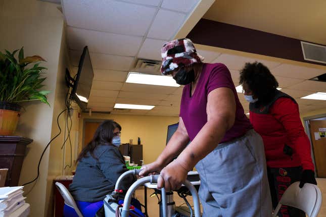 A woman approaches her seat while a medical technician waits to administer her COVID-19 vaccine on February 12, 2021 in Louisville, Kentucky, the first day that Norton Healthcare offered the vaccination in predominantly black areas of the city. 