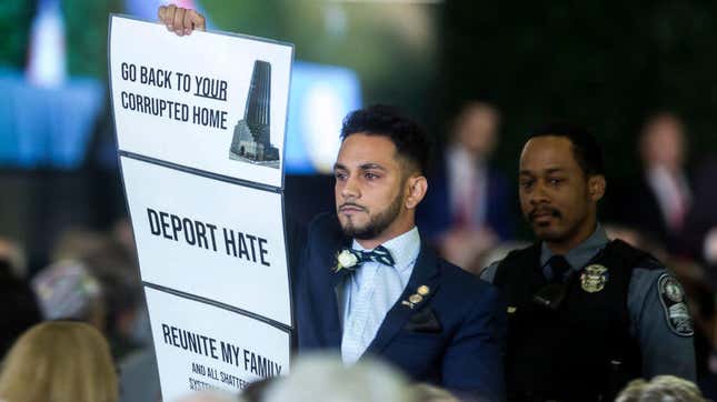 Virginia state Del. Ibraheem Samirah holds up a sign as Donald Trump delivers remarks during the 400th anniversary celebration of the first representative legislative assembly at Jamestown on July 30, 2019, in Jamestown, Va. 