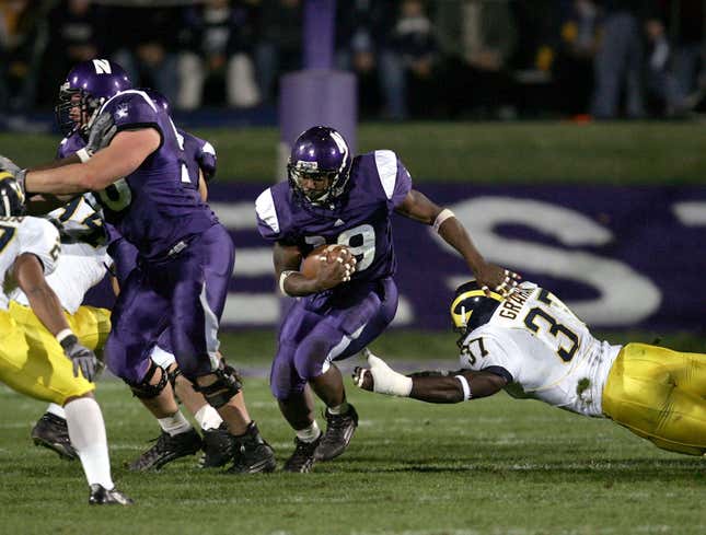 Running back Tyrell Sutton #19 of the Northwestern Wildcats follows the block of lineman Ryan Keenan #56 as linebacker Chris Graham #37 of the Michigan Wolverines dives for a tackle during a game on October 29, 2005 at Ryan Field at Northwestern University in Evanston, Illinois.