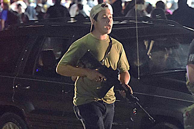 In this Tuesday, Aug. 25, 2020 file photo, Kyle Rittenhouse carries a weapon as he walks along Sheridan Road in Kenosha, Wis., during a night of unrest following the weekend police shooting of Jacob Blake.