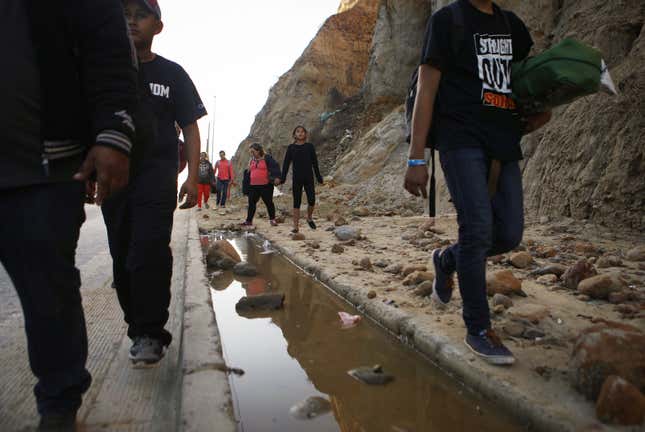 Migrants attempting to reach the U.S. walk along a highway toward the U.S.-Mexico border fence near Tijuana, Mexico.