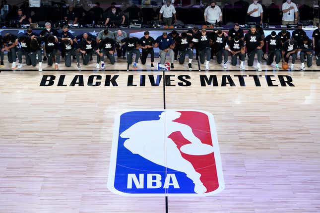 Members of the New Orleans Pelicans and Utah Jazz kneel before a Black Lives Matter logo before the start of their game at HP Field House at ESPN Wide World Of Sports Complex on July 30, 2020 in Reunion, Florida.