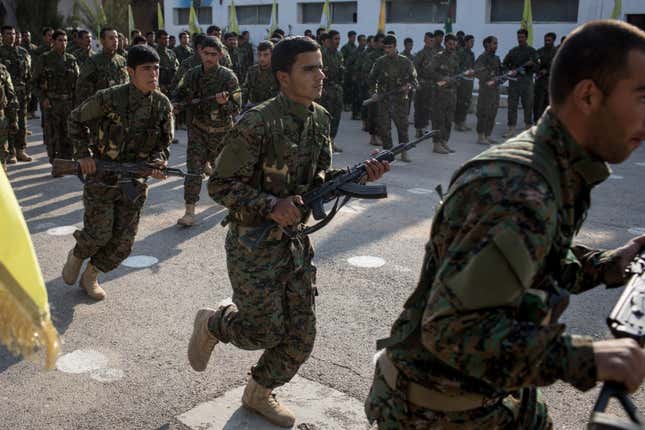 Syrian Democratic Forces (SDF) fighters perform in a parade march during a SDF victory ceremony announcing the defeat of ISIL in Baghouz held at Omer Oil Field on March 23, 2019 in Deir Al Zor, Syria.