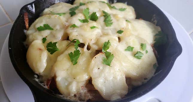 Tartiflette in cast iron skillet on white countertop