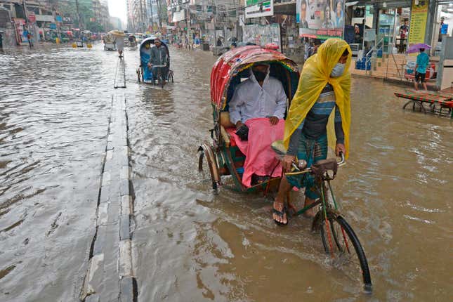 Rickshaw pullers make their way through a water-logged street after a heavy downpour in Dhaka on June 21, 2020.