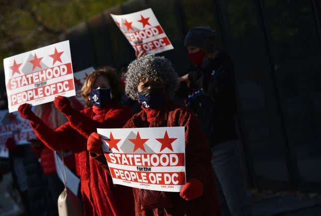 Activists hold signs as they take part in a rally in support of DC statehood near the US Capitol in Washington, DC on March 22, 2021.