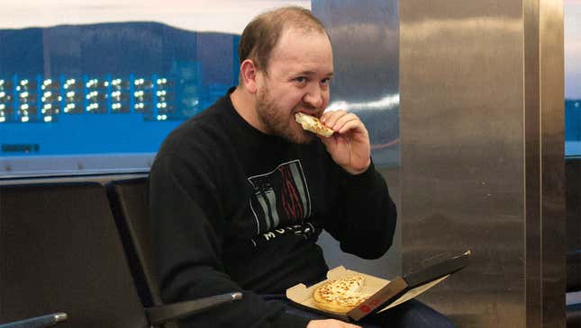 Image for article titled Man Silently Eating Personal Pan Pizza Alone In Corner Of Airport Unaware This Will Be Best Part Of 7-Day Vacation