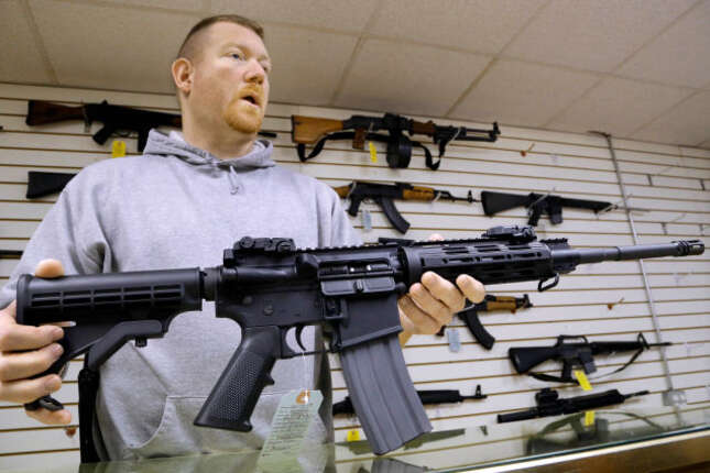 John Jackson, co-owner of Capitol City Arms Supply shows off an AR-15 assault rifle for sale Wednesday, Jan. 16, 2013 at his business in Springfield, Ill.