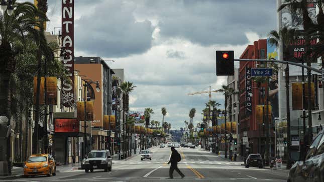 LOS ANGELES, CALIFORNIA - MARCH 25: A man crosses the unusually quiet Hollywood Boulevard near the shuttered Pantages Theatre as the coronavirus pandemic continues on March 25, 2020 in Los Angeles, California.