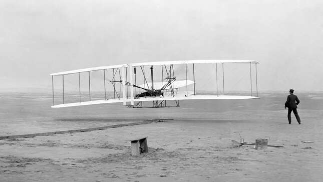 Orville Wright, lying at the controls on the lower wing, pilots the Wright Flyer on the first powered flight by a heavier-than-air aircraft, Dec. 17, 1903, at Kitty Hawk, N.C