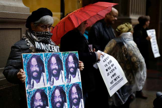 A protester holds up a poster depicting Mumia Abu-Jamal during a demonstration Dec. 28, 2018, outside the offices of Philadelphia District Attorney Larry Krasner.