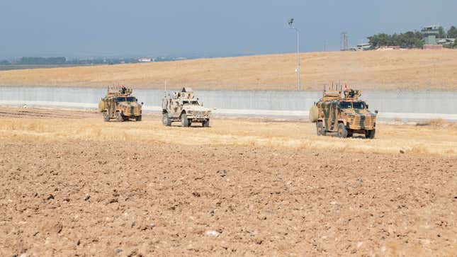 US troops, center, conduct a joint patrol with Turkish armored vehicles in Northeastern Syria.