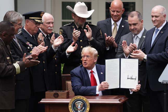 Surrounded by members of law enforcement, U.S. President Donald Trump holds up an executive order he signed on “Safe Policing for Safe Communities” during an event in the Rose Garden at the White House June 16, 2020 in Washington, DC.
