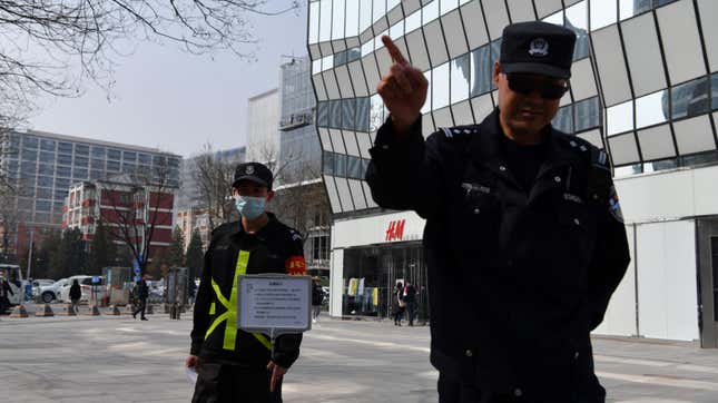 A cop tries to prevent photos from being taken outside an H&amp;M store in Beijing on March 25, 2021.