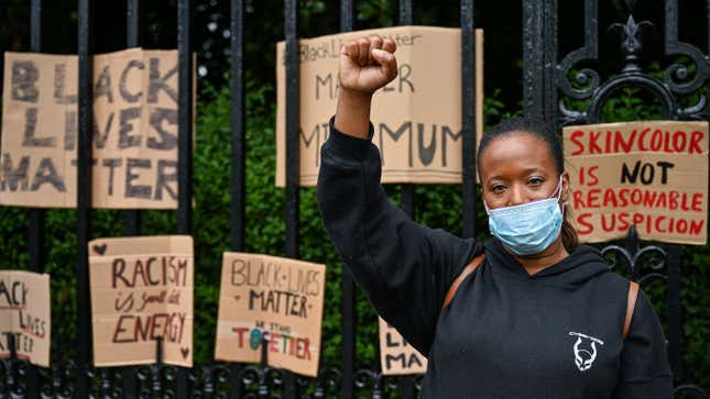 A woman raises her fist in the air as Black Lives Matter protesters hang their banners on the fence on June 7, 2020, in Edinburgh, Scotland.