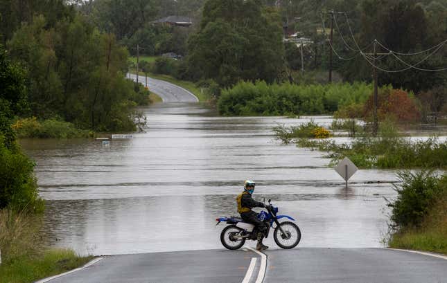 A motorcyclist’s progress is blocked by a flooded road at Old Pitt Town, northwest of Sydney.