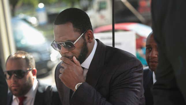 R. Kelly covers his mouth as he speaks to members of his entourage as he arrives at the Leighton Criminal Courts Building for a hearing on June 26, 2019 in Chicago, Illinois. 