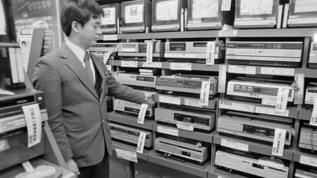 A sales clerk at an electronics store in the Akihabara district of Tokyo, Japan, displays a stack of video cassette recorders (VCR), which are on sale for 20 to 30 percent off, Dec. 15, 1981.