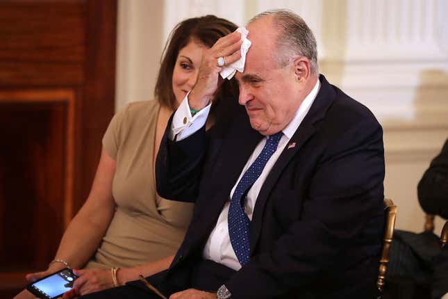 Rudy Giuliani (right) wipes his brow July 9, 2018, as Donald Trump introduces Brett Kavanaugh as his nominee to the U.S. Supreme Court. 