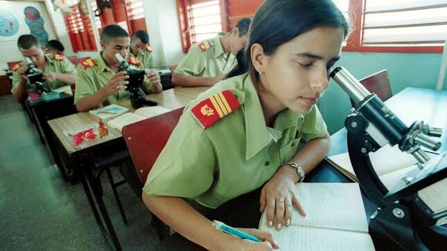 Yumara Borges, 15, and other students look through microscopes as they study at a laboratory November 26, 2001 at the School of the Army ‘Camilo Cienfuegos’ near Havana, Cuba.