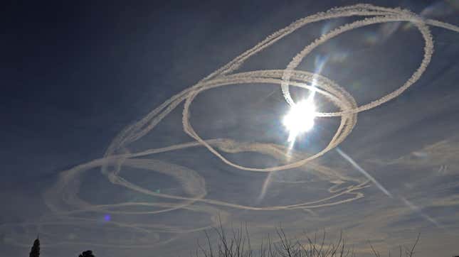 Aircraft contrails circle the sun above the Old City of Jerusalem on January 26, 2021. 