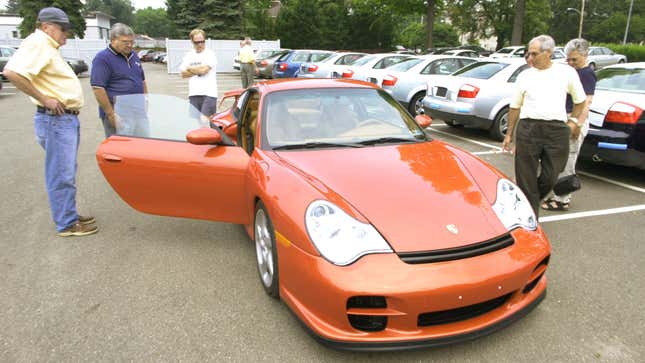 A group of visitors to a Porsche and Audi dealership in Sewickley, Pa. looks over Bob Nikel’s, left, new 2002 Porsche 911 GT2 on Friday, July 19, 2002. Americans’ ravenous appetite for foreign-made cars, TVs and clothes propelled the U.S. trade deficit to a record $37.6 billion in May. (AP Photo/Keith Srakocic)
