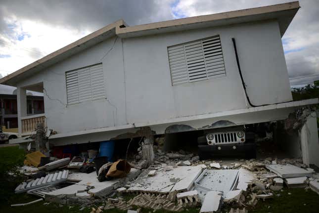 A car is crushed under a home that collapsed after the previous day’s  magnitude 6.4 earthquake in Yauco, Puerto Rico, Jan. 8, 2020.  More than 250,000 Puerto Ricans remained without water on Wednesday and  another half a million without power, which also affected  telecommunications.