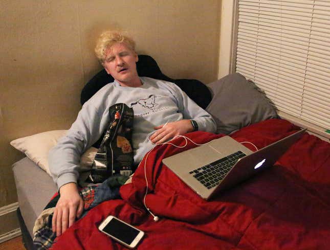 Image for article titled Sleeping Man Flanked By Laptop, Phone, Earbuds Like Egyptian Pharaoh Buried With All His Treasures
