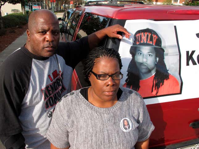 In this Dec. 13, 2013 file photo, Kenneth and Jacquelyn Johnson stand next to a banner on their SUV showing their late son, Kendrick Johnson in Valdosta, Ga. A Georgia sheriff said Wednesday, March 10, 2021, he’s reopened an investigation into the 2013 death of the teenager, whose body was found inside a rolled-up gym mat at his high school. 