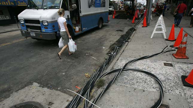  A woman walks past power lines on the sidewalk as workers try to restore electrical service July 23, 2006 in the Queens borough of New York City. 