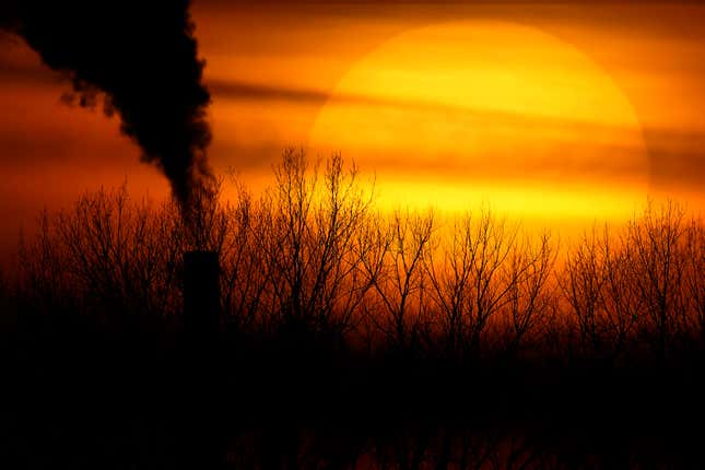 Emissions from a coal-fired power plant are silhouetted against the setting sun in Independence, Mo.