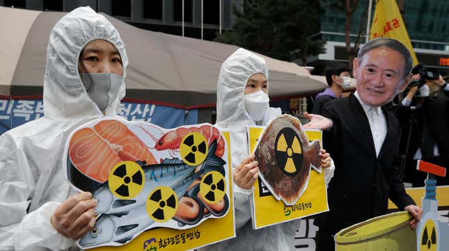 Environmental activists wearing a mask of Japanese Prime Minister Yoshihide Suga and protective suits protest the government’s decision in Seoul, South Korea.