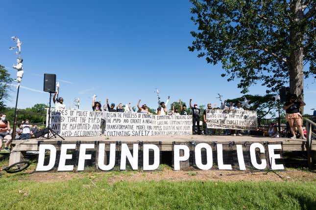 Members of the Black Visions Collective and Reclaim the Block hold banners outlining the City Council’s plan to dismantle the police department.