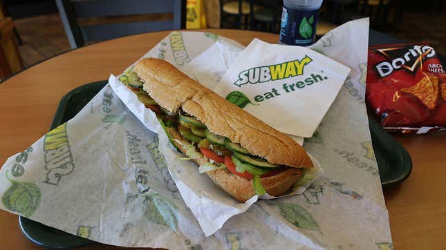 Subway footlong unwrapped on a tray at a Subway restaurant table