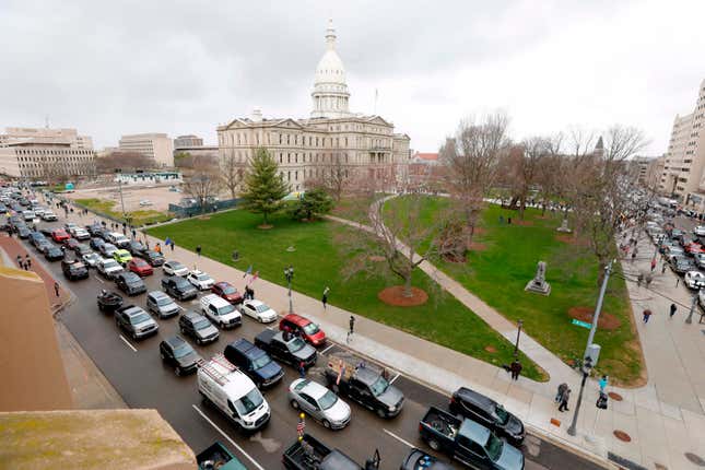 People in their vehicles protest against excessive quarantine orders from Michigan Governor Gretchen Whitmer around the Michigan State Capitol in Lansing, Michigan on April 15, 2020. - The protest was organized by Michiganders Against Excessive Quarantine several days after Michigan Governor Gretchen Whitmer extended her order through April 30 and took the requirements of staying home a step further, banning crossing the street to visit with neighbors or driving to see friends, among other things mandatory closure to curtail Covid-19.