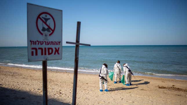 Israeli soldiers wearing protective suits clean tar from an oil spill in the Mediterranean Sea.