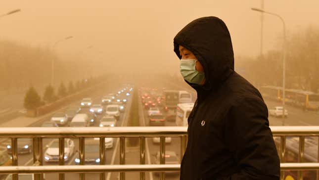 A man walks on a pedestrian overbridge during a sandstorm in Beijing as traffic crawls in the background on March 15, 2021.